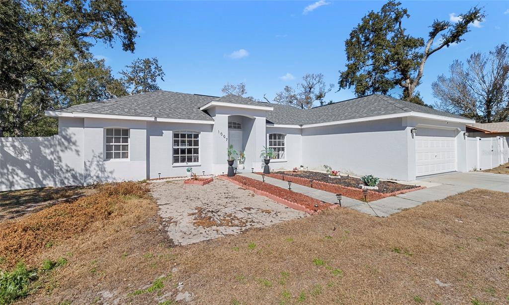 A single-story house with a gray exterior, a white garage door, and a front walkway — 1007 TRYON CIRCLE, SPRING HILL, FL