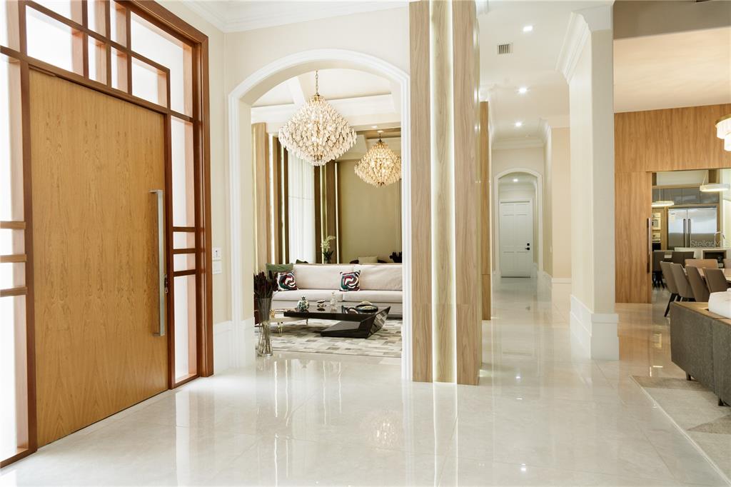 A bright foyer with light tile flooring leads to a living room with crystal chandeliers — 6719 VALHALLA WAY, WINDERMERE, FL