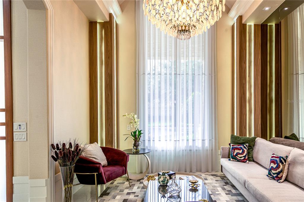 A living room features a crystal chandelier, tall windows with sheer curtains, and wood-paneled walls — 6719 VALHALLA WAY, WINDERMERE, FL