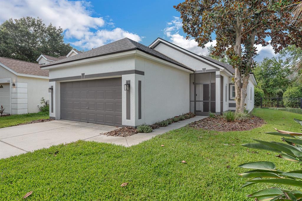 A single-story house with a two-car garage, stucco exterior, and a screened front entryway — 6116 SKYLARKCREST DRIVE, LITHIA, FL