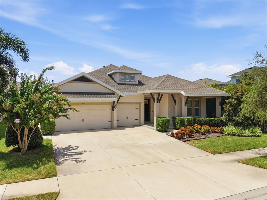A single-story house with a beige exterior, a two-car garage, and a landscaped front yard — 7720 PARADISO DRIVE, APOLLO BEACH, FL