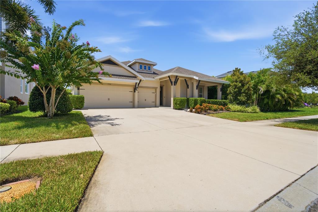 A single-story house with a beige exterior, a three-car garage, and a landscaped front yard — 7720 PARADISO DRIVE, APOLLO BEACH, FL