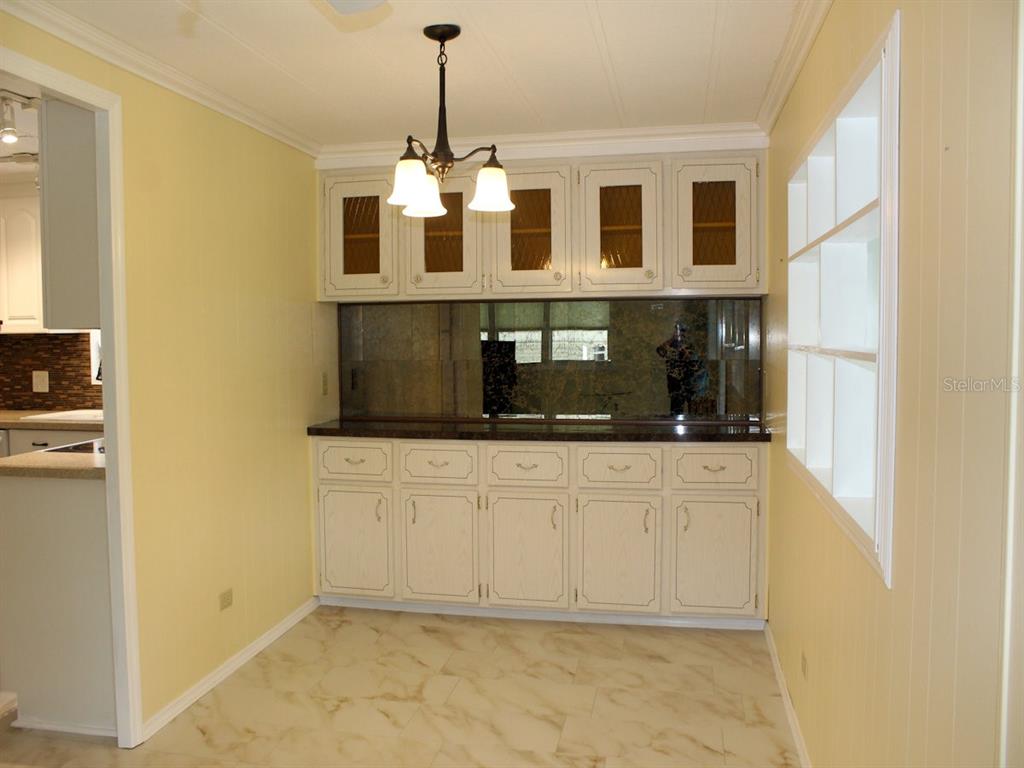 A dining area features light yellow walls, white cabinetry, a mirrored backsplash, and tile flooring — 92 THATCH PALM STREET E, LARGO, FL