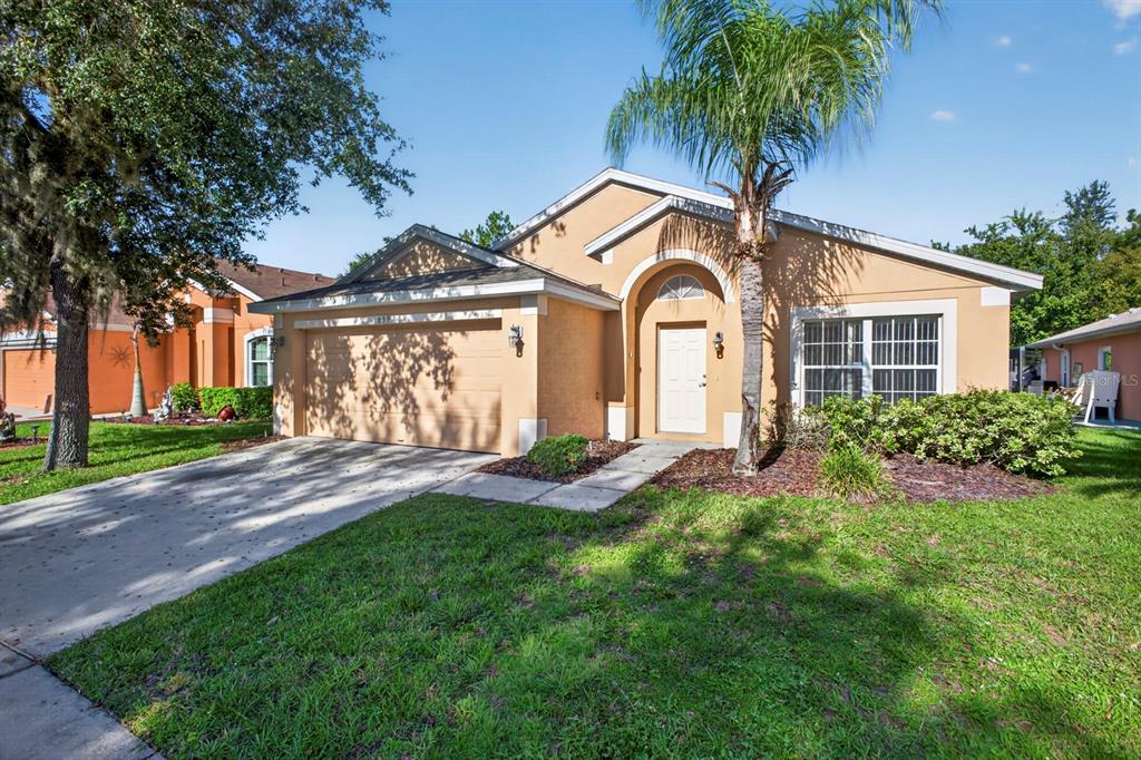 A single-story tan stucco house with a two-car garage, palm tree, and front lawn — 839 SANDY RIDGE DRIVE, DAVENPORT, FL