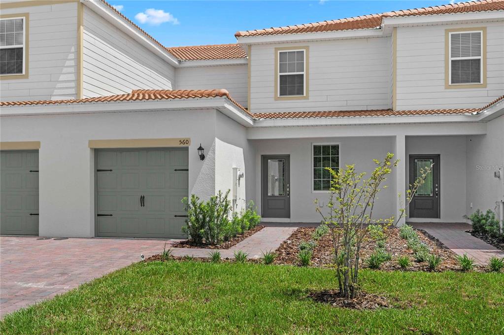 The exterior of a two-story townhouse features a garage, a front entrance, and landscaping — 576 BAY LEAF DRIVE, POINCIANA, FL