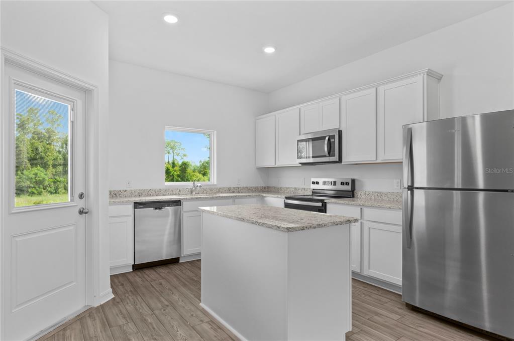 A kitchen features white cabinets, granite countertops, stainless steel appliances, and a central island — 576 BAY LEAF DRIVE, POINCIANA, FL
