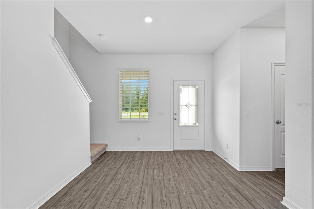 An entryway with wood-look flooring, a white front door, a window, and a staircase — 576 BAY LEAF DRIVE, POINCIANA, FL
