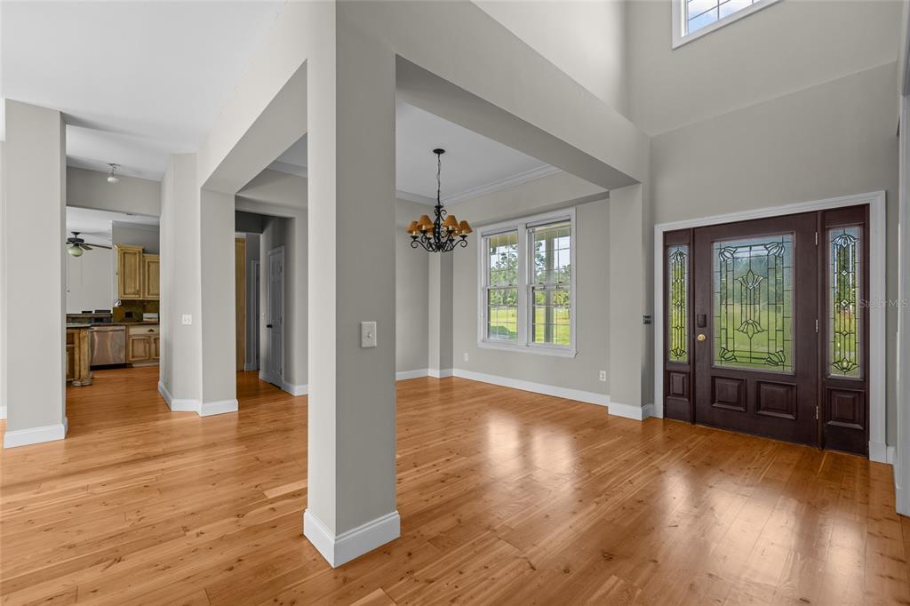 An entryway with hardwood floors, a dark wood front door, and a formal dining area — 10852 89TH ROAD, LIVE OAK, FL