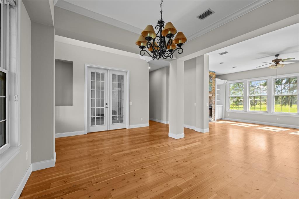 An empty room with hardwood floors, a chandelier, French doors, and large windows — 10852 89TH ROAD, LIVE OAK, FL