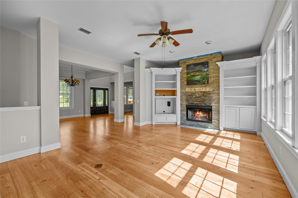 A living room features hardwood floors, a stone fireplace, built-in shelving, and a ceiling fan — 10852 89TH ROAD, LIVE OAK, FL