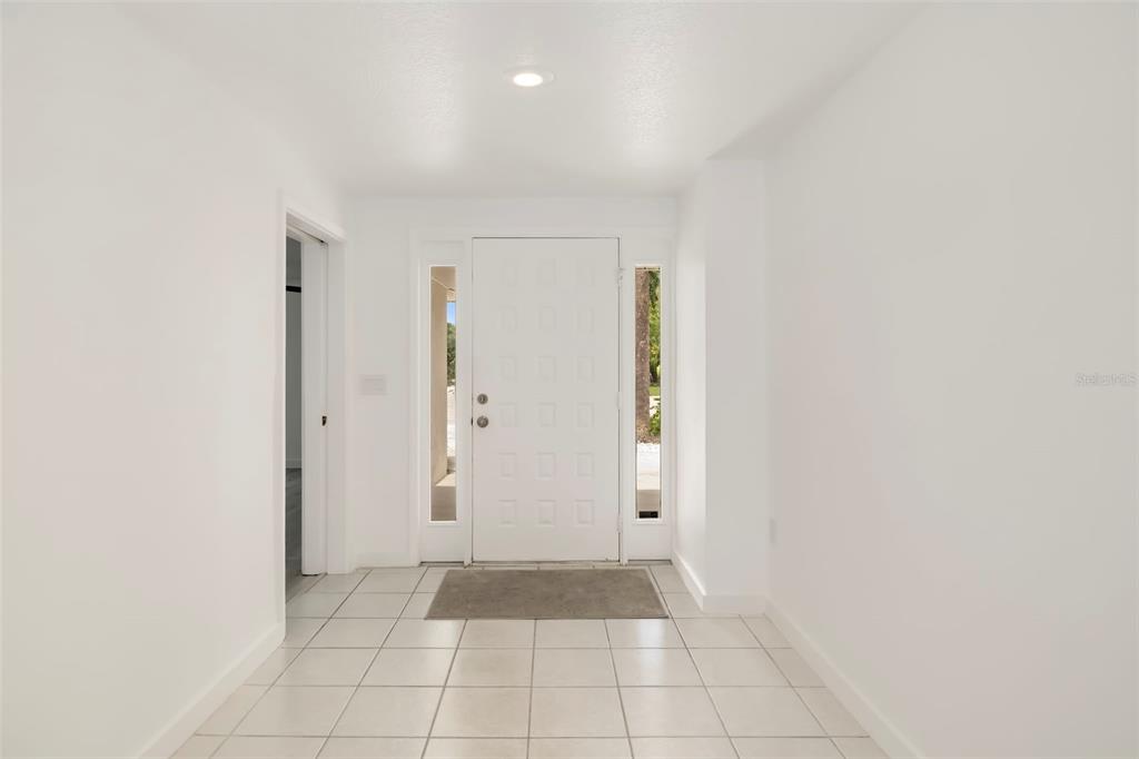 A bright entryway features white walls, light-colored tile flooring, and a white front door — 708 GARFIELD DRIVE, SARASOTA, FL