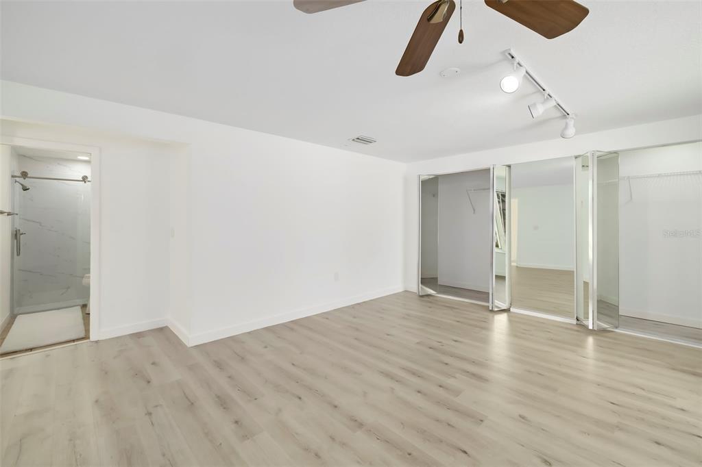 A bedroom with light wood-look flooring, a ceiling fan, track lighting, and mirrored closet doors — 708 GARFIELD DRIVE, SARASOTA, FL