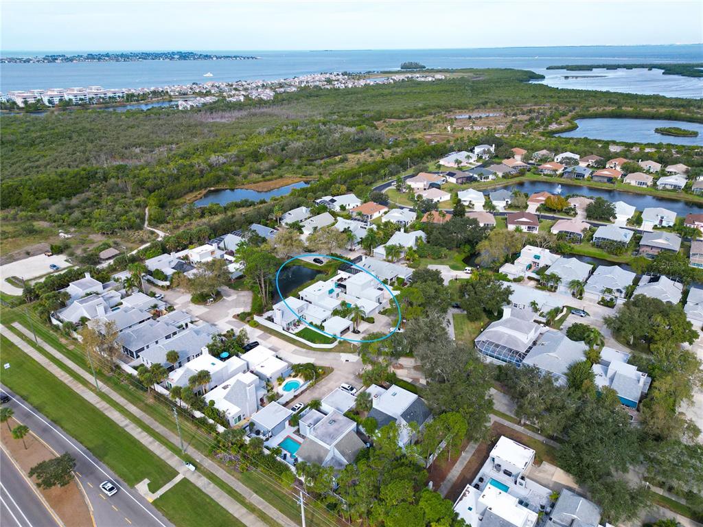 An aerial view shows a residential neighborhood with houses, pools, and a nearby bay — 11213 VERANDA COURT, BRADENTON, FL