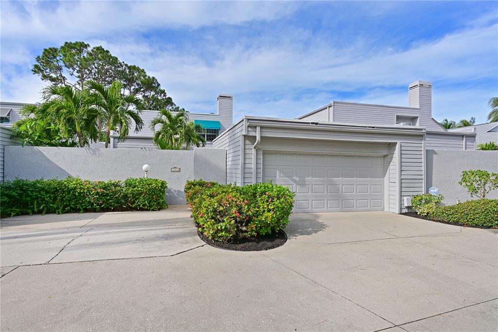 A gray house exterior features a two-car garage, a concrete driveway, and lush landscaping — 11213 VERANDA COURT, BRADENTON, FL