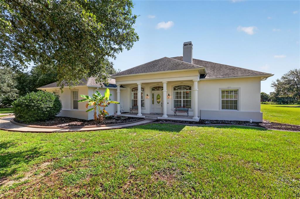 A single-story house with a white stucco exterior, a covered front porch, and a chimney — 32542 SCENIC HILLS DRIVE, MOUNT DORA, FL