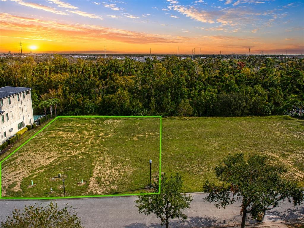 An aerial view shows a vacant, rectangular residential lot outlined in green next to a building — 560 MUIRFIELD LOOP, REUNION, FL