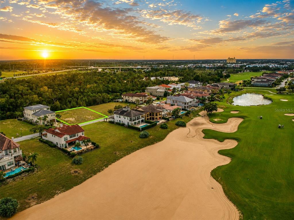 An aerial view shows a vacant residential lot outlined in green next to a golf course — 560 MUIRFIELD LOOP, REUNION, FL