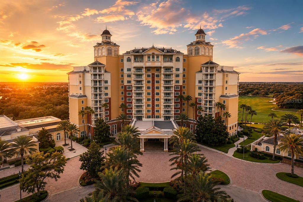 An aerial view of a large, multi-story hotel building with palm trees at sunset — 560 MUIRFIELD LOOP, REUNION, FL
