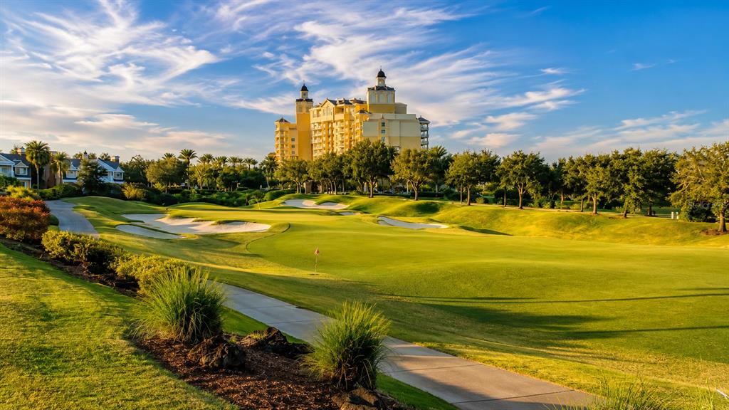 A golf course fairway leads toward a large multi-story resort building under a blue sky — 560 MUIRFIELD LOOP, REUNION, FL
