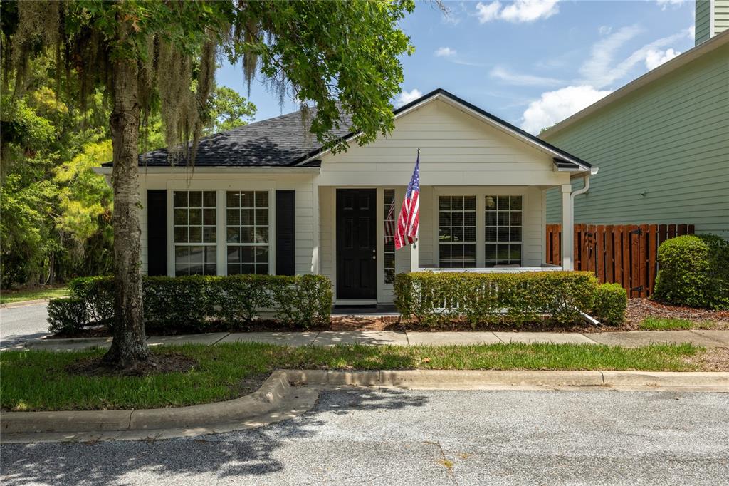A single-story white house with a front porch, black shutters, and an American flag — 11684 NW 18TH PLACE, GAINESVILLE, FL
