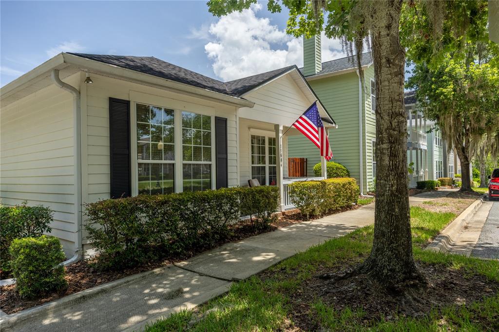 A white single-story house with black shutters and an American flag on the front porch — 11684 NW 18TH PLACE, GAINESVILLE, FL