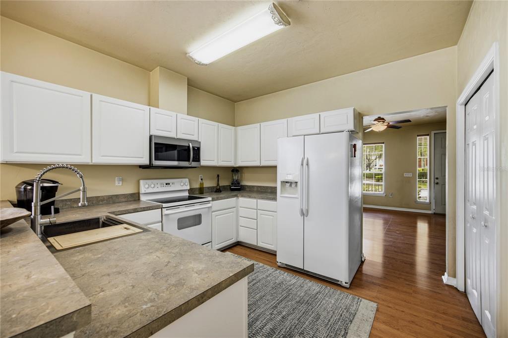 A kitchen with white cabinets, a white refrigerator, a microwave, and tan countertops — 11684 NW 18TH PLACE, GAINESVILLE, FL