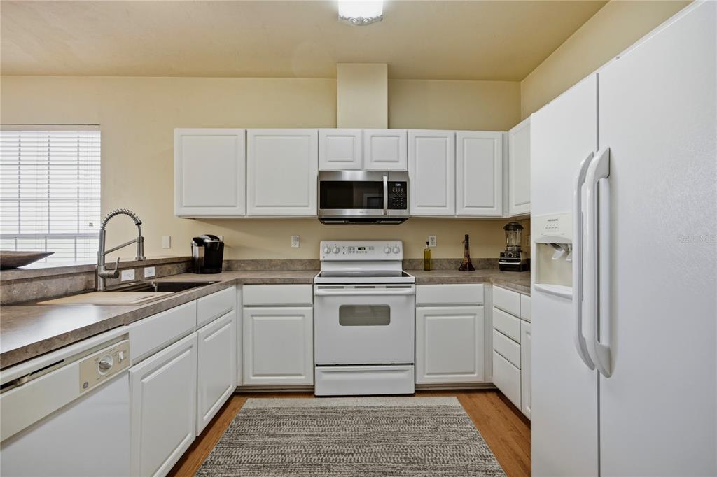 A kitchen features white cabinets, stainless steel appliances, a white stove, and laminate countertops — 11684 NW 18TH PLACE, GAINESVILLE, FL