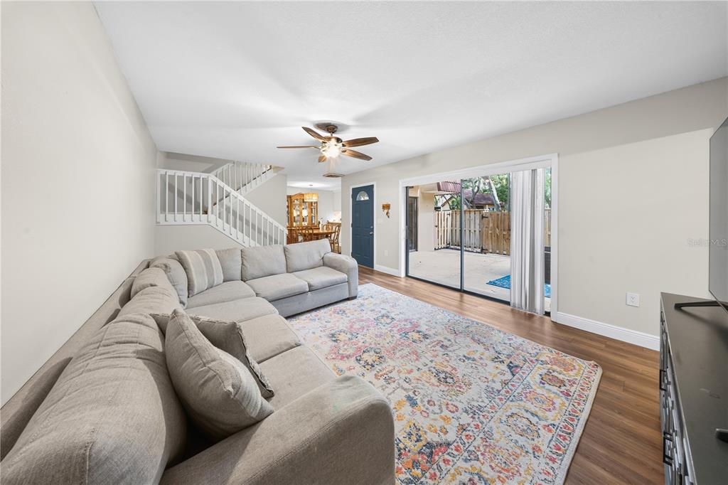 A living room with a sectional sofa, a patterned rug, and a sliding glass door — 680 1ST COURT, PALM HARBOR, FL