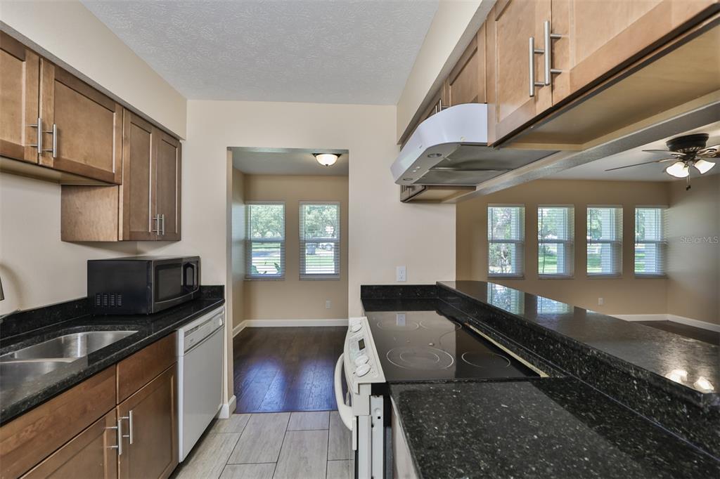 A kitchen features dark granite countertops, wood cabinets, stainless steel appliances, and tile flooring — 105 N KINGSWAY ROAD, SEFFNER, FL