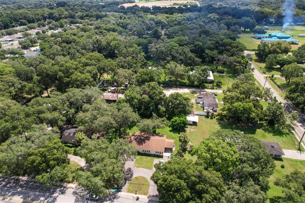 An aerial view shows a residential property with multiple buildings surrounded by dense trees — 105 N KINGSWAY ROAD, SEFFNER, FL