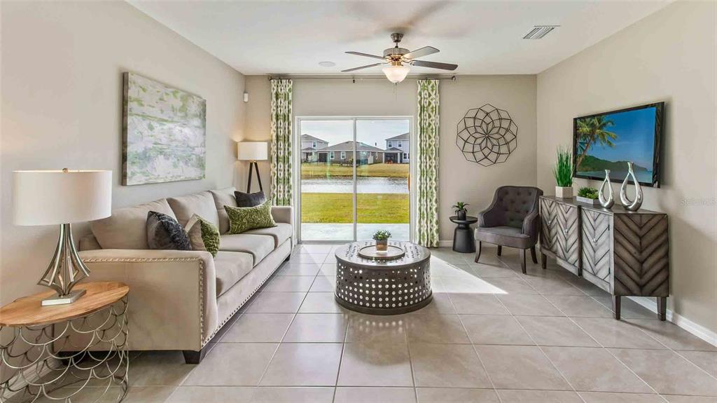 A living room features a beige sofa, a round metal coffee table, and sliding glass doors — 4540 HIDDEN FARM DRIVE, PLANT CITY, FL