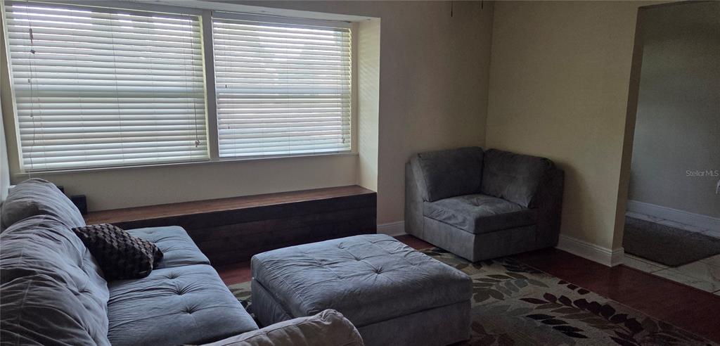 A living room features a gray sectional sofa, a matching ottoman, and a built-in wooden bench — 225 YARMOUTH ROAD, FERN PARK, FL