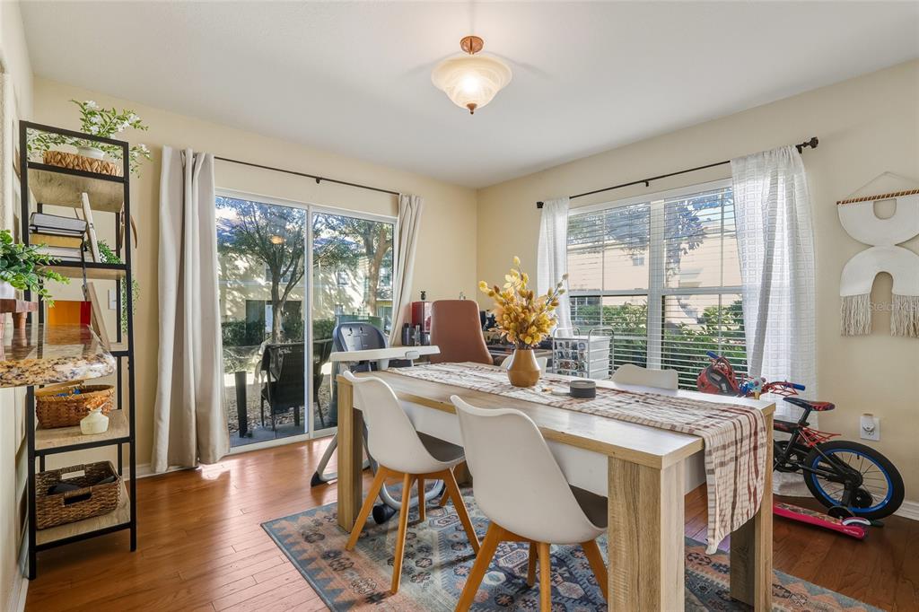 A dining room with a wooden table, white chairs, hardwood floors, and a sliding glass door — 10952 KEYS GATE DRIVE, RIVERVIEW, FL