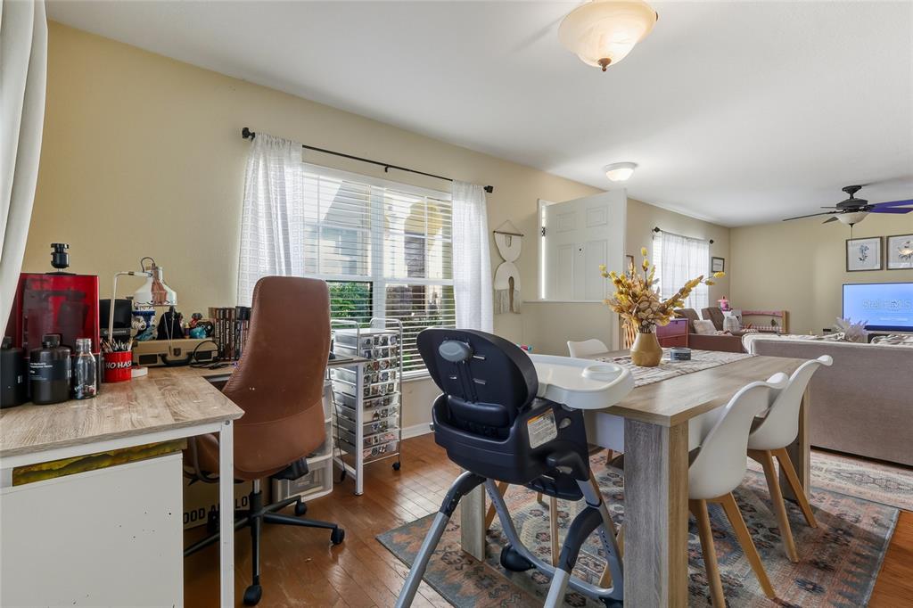A dining area with a high chair, a desk, and a living room in the background — 10952 KEYS GATE DRIVE, RIVERVIEW, FL
