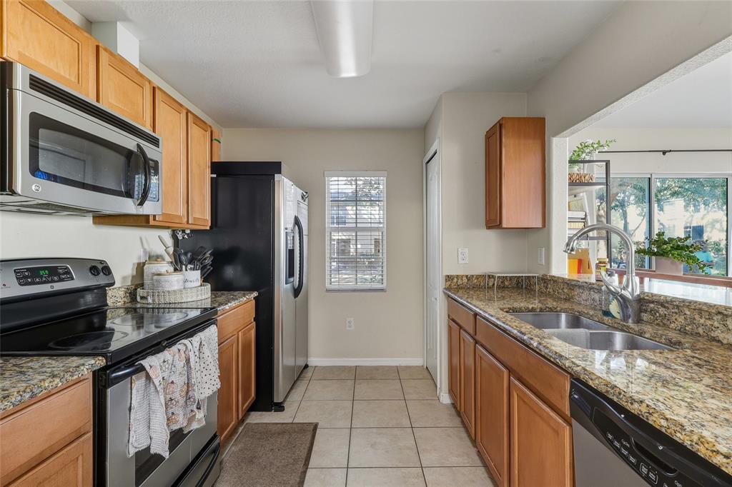 A kitchen features wood cabinets, granite countertops, stainless steel appliances, and tile flooring — 10952 KEYS GATE DRIVE, RIVERVIEW, FL