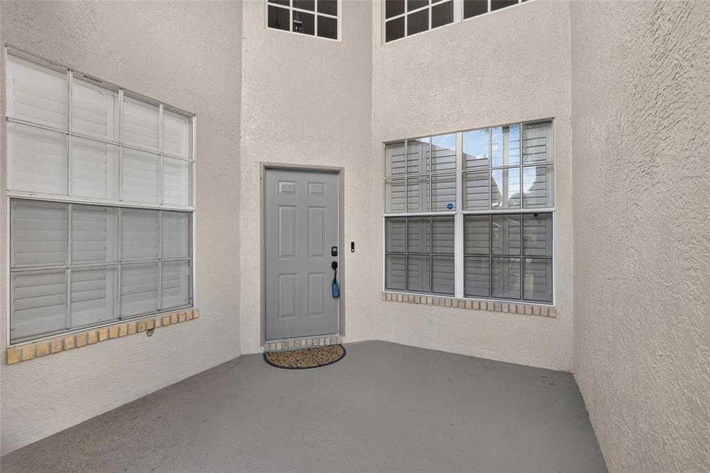 A gray front door is centered between two windows on a concrete porch — 2205 PRESERVATION DRIVE, PLANT CITY, FL