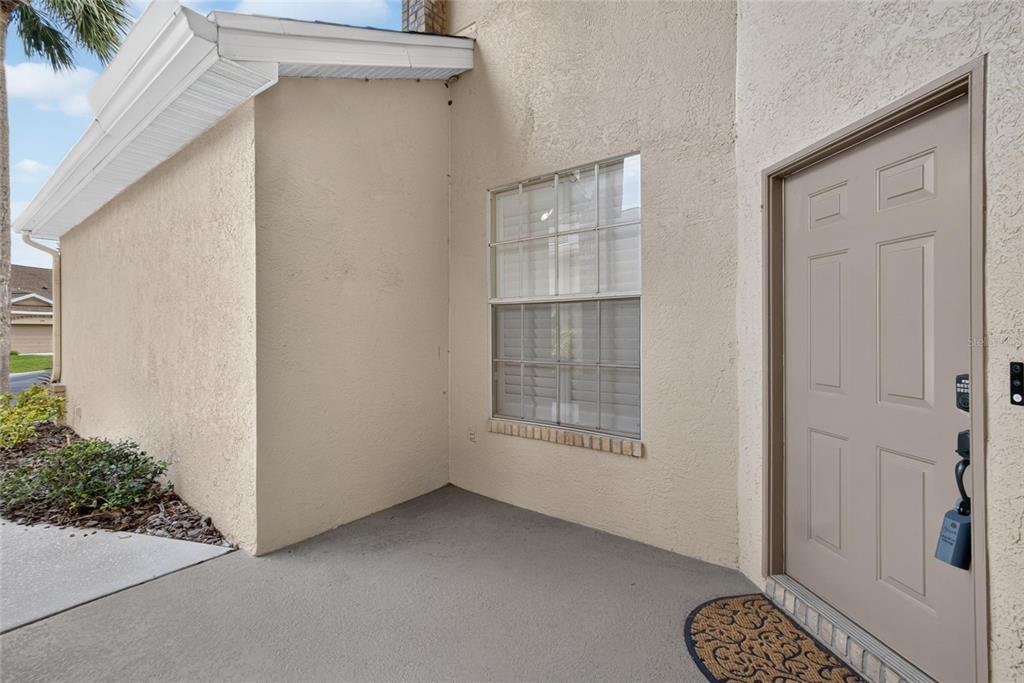 A beige stucco exterior wall features a single window and a tan front door — 2205 PRESERVATION DRIVE, PLANT CITY, FL