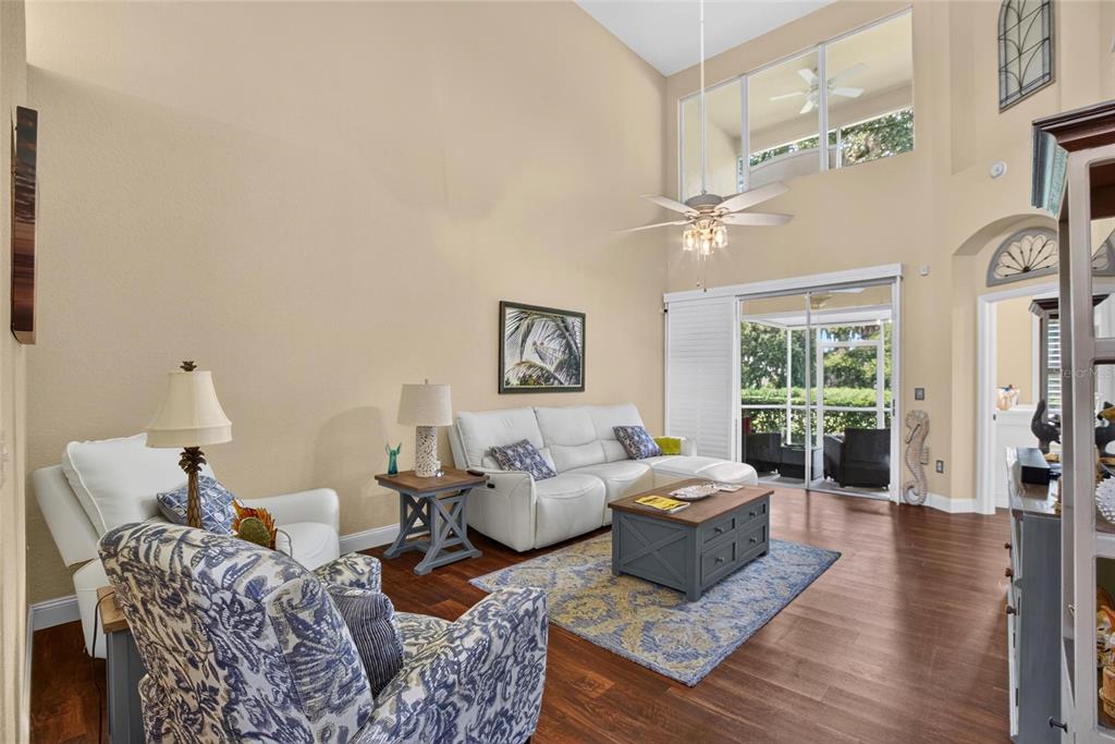 A living room with high ceilings, a white sofa, patterned armchair, and sliding glass doors — 2205 PRESERVATION DRIVE, PLANT CITY, FL