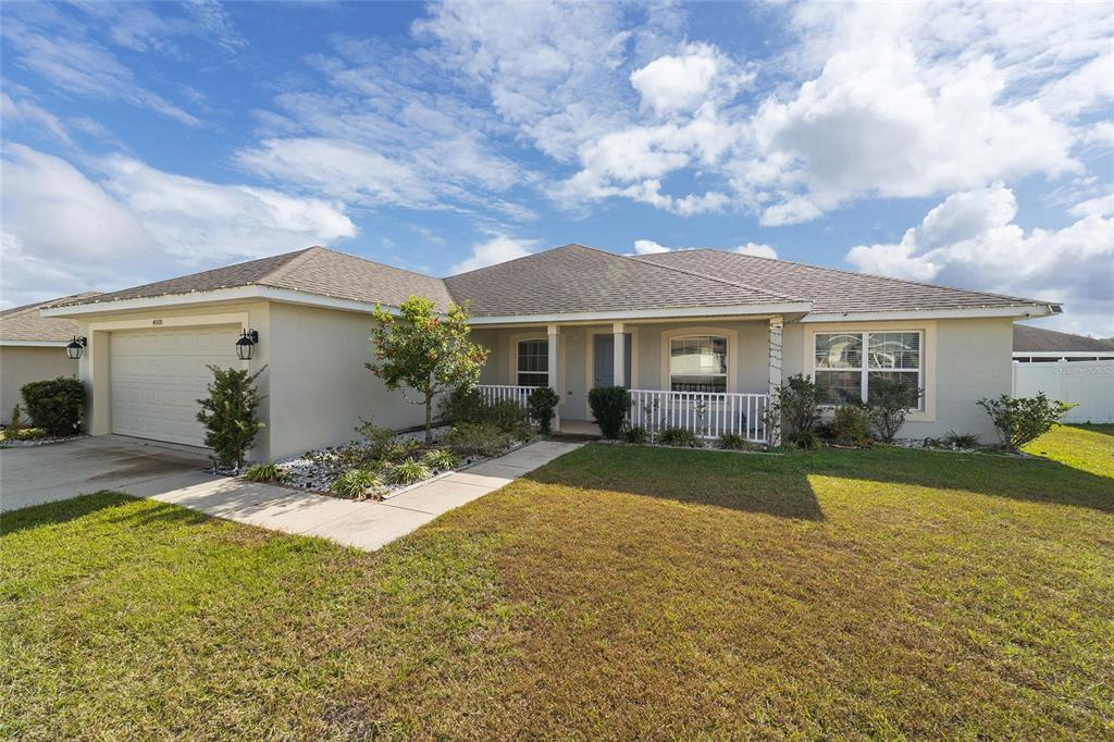 A single-story house with a beige stucco exterior, a two-car garage, and a front porch — 4000 SE 98TH PLACE, BELLEVIEW, FL