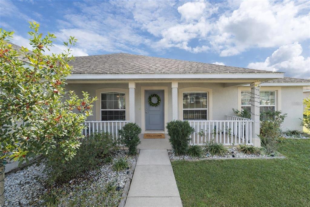 A single-story house with a gray front door, white porch railing, and a concrete walkway — 4000 SE 98TH PLACE, BELLEVIEW, FL