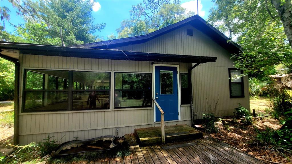 A light-colored house with a blue door, large windows, and a wooden deck — 8664 CR 639, BUSHNELL, FL