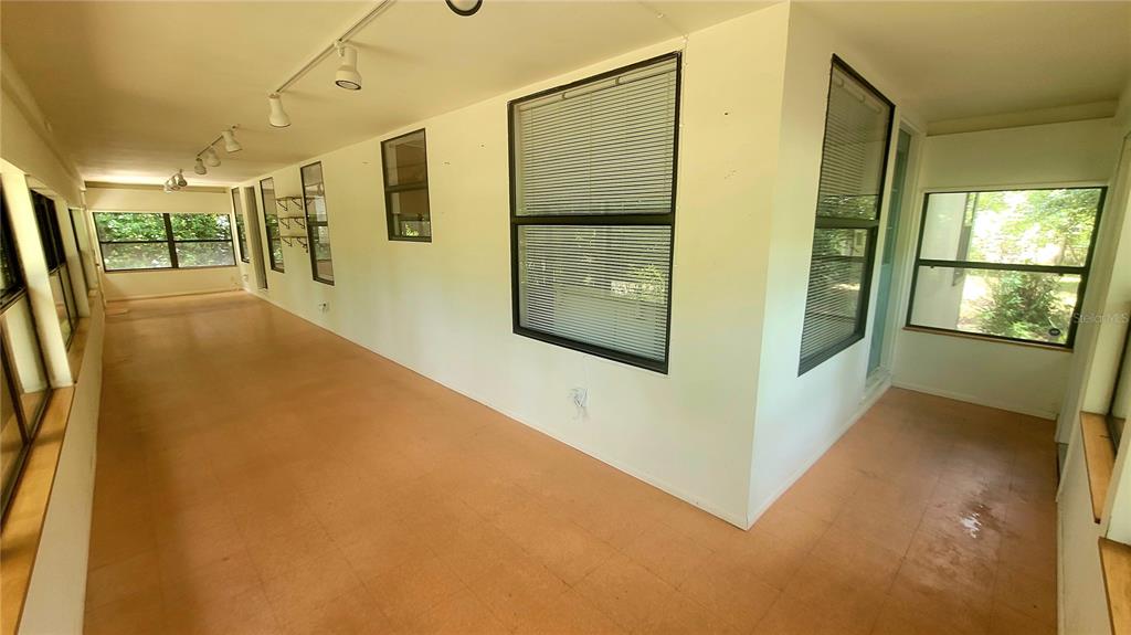 A sunroom features light-colored tile flooring, white walls, and multiple windows with blinds — 8664 CR 639, BUSHNELL, FL