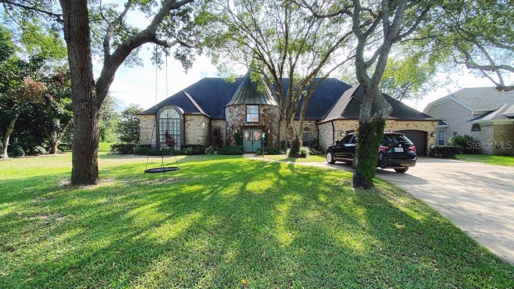 A brick house with a turret entrance and a large front yard with trees — 27 LAKE VISTA WAY, ORMOND BEACH, FL