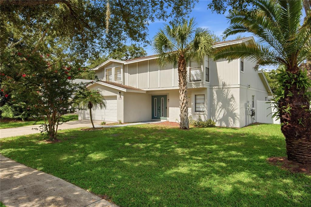 A two-story house with light-colored vertical siding, a front-facing garage, and a palm tree — 4509 GRAINARY AVENUE, TAMPA, FL