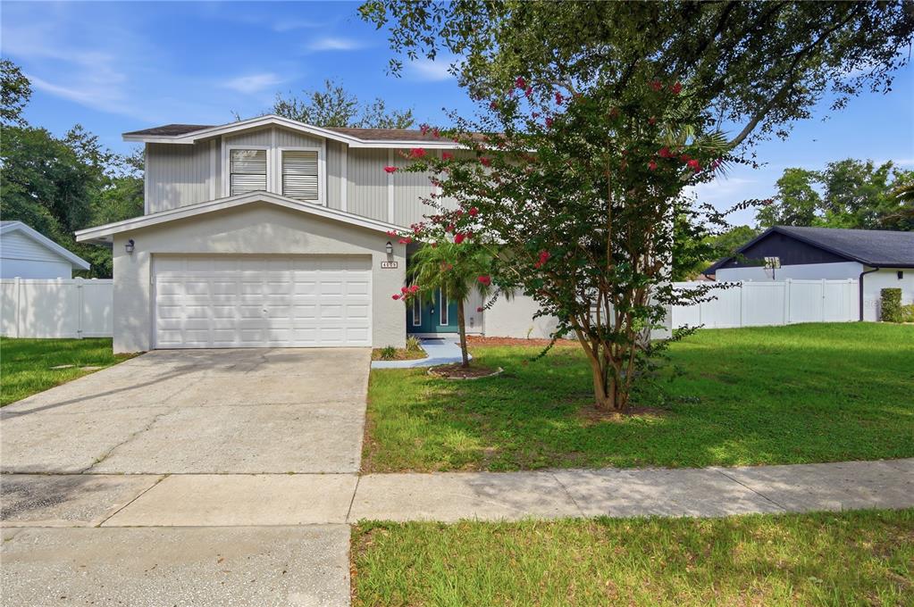 A two-story house with a white garage, light siding, and a flowering tree in the yard — 4509 GRAINARY AVENUE, TAMPA, FL