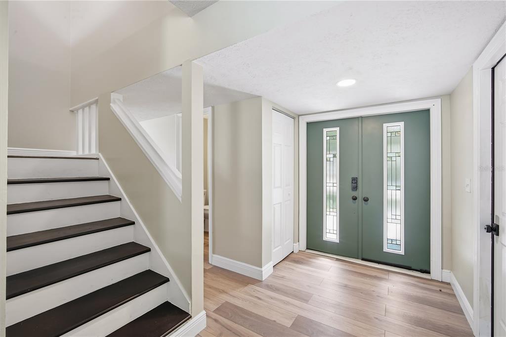 An entryway features a double green door, wood-look flooring, and a staircase with dark treads — 4509 GRAINARY AVENUE, TAMPA, FL