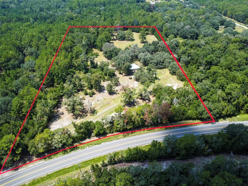 An aerial view shows a house situated on a large, wooded lot bordering a road — 28622 N STATE ROAD 121, ALACHUA, FL