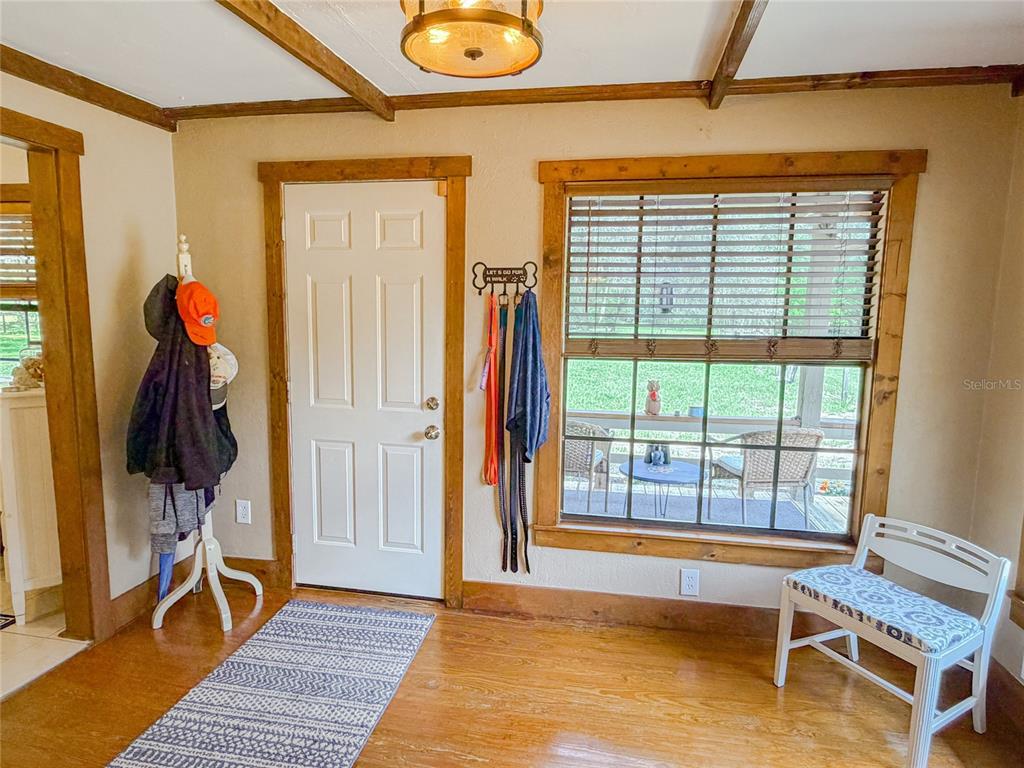 An entryway features hardwood floors, a white door, a window with blinds, and a coat rack — 28622 N STATE ROAD 121, ALACHUA, FL