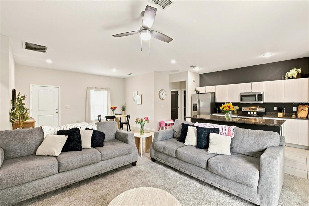 A living room with two gray sofas faces an open kitchen with dark countertops — 5724 BANNOCK CIRCLE, NORTH PORT, FL