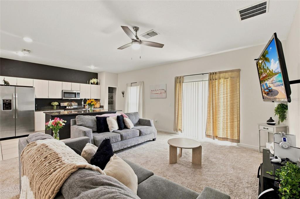 A living room with gray sofas, a coffee table, and an open-concept kitchen — 5724 BANNOCK CIRCLE, NORTH PORT, FL